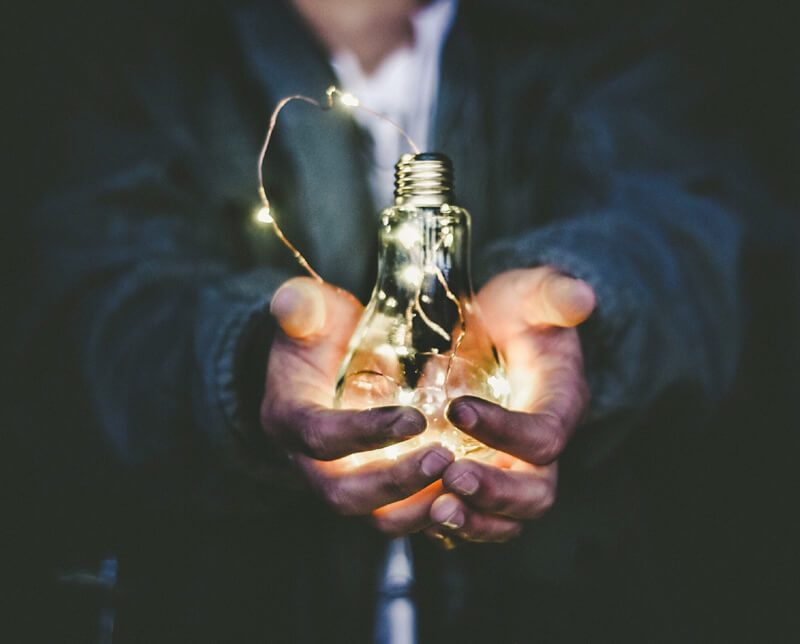 Photo of man's hands holding a glowing light bulb